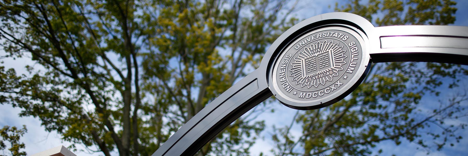 Indiana University seal on a metal arch in front of a blue sky