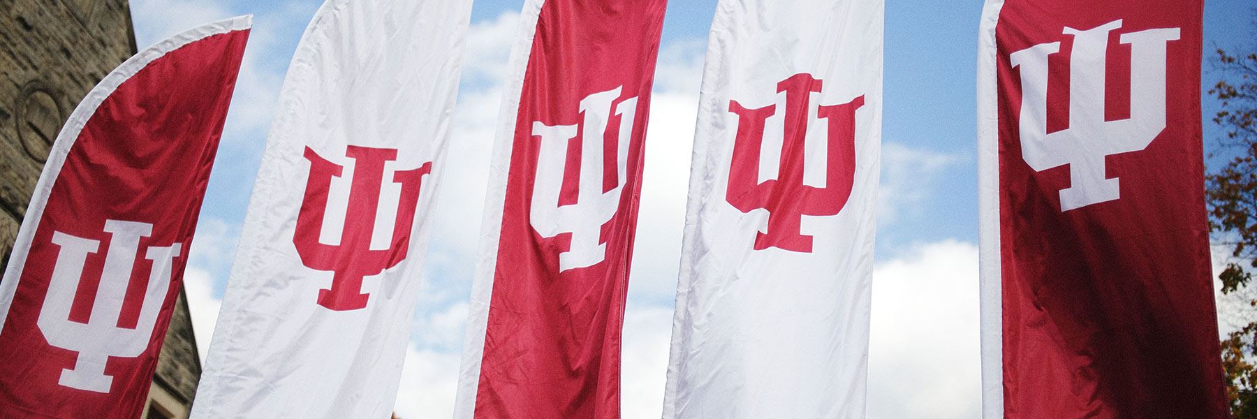 A row of red and white outdoor banners with the IU trident